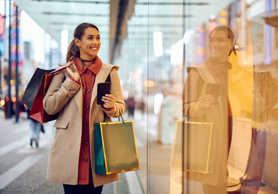 Young happy woman enjoying in window shopping in city.